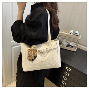 Close-up of cream white tote bag featuring crocodile texture and floral silk scarf detail