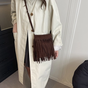Brown faux suede crossbody bag with tassels and shoulder strap shown on a model