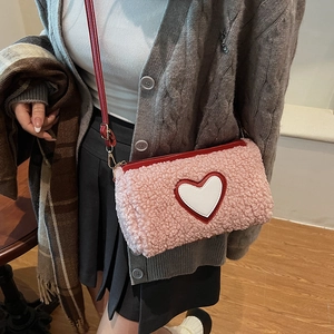 Sac seau chic en peluche rose avec motif cœur et bandoulière en cuir rouge