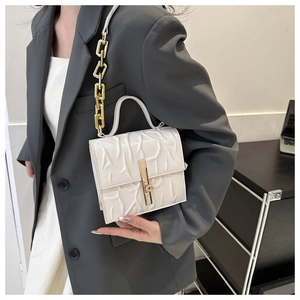 Close-up of white embossed branch texture and gold chain strap on a stylish shoulder bag