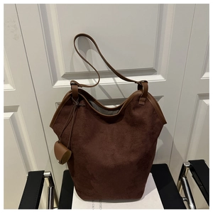 Detailed macro view of dark brown suede tote bag featuring a matching mini pouch charm