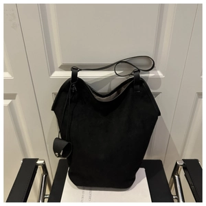 Detail of a large black suede tote bag with slim shoulder straps on a chair
