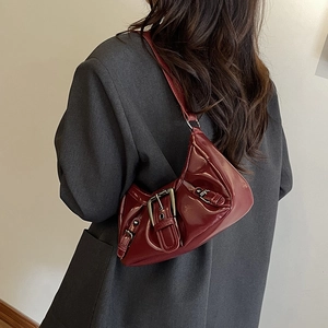 Schicke weinrote Lackleder-Unterarmtasche mit Metallschnalle getragen zum grauen Blazer