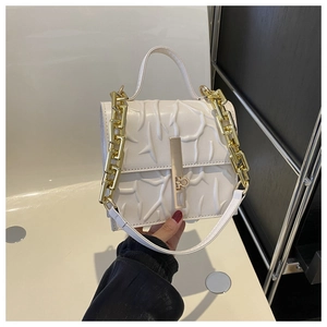Close-up of elegant white chain bag with branch-style embossing and golden hardware