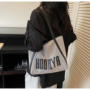 Detailed view of high-quality canvas tote bag with black embroidered text and leather straps