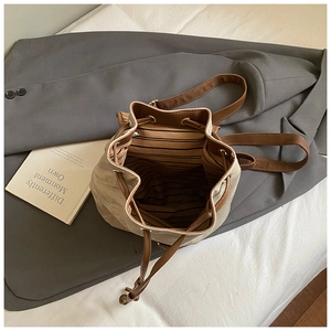 Dettaglio di zaino vintage in tela con finiture in pelle marrone e fodera a righe