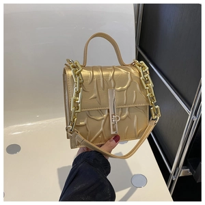 Detail of champagne gold handbag featuring embossed coral textures and a chunky chain strap
