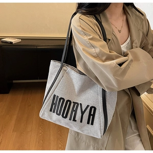 Detail of high-quality canvas tote bag with black HOORYA embroidery and leather strap