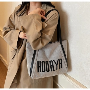 Close-up of the large canvas tote bag featuring HOORYA logo and black leather straps