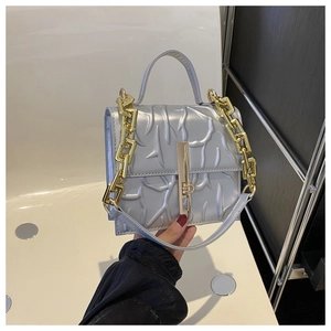 Detailed close-up of metallic silver faux leather bag with embossed texture and gold chain