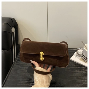 Detail of dark brown matte suede texture and gold buckle on a stylish underarm bag