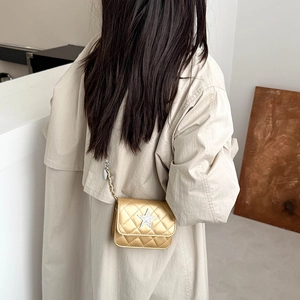 Mini gold quilted chain bag with star detail worn over a stylish beige autumn coat