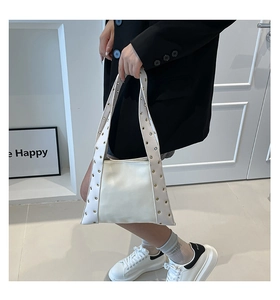 Gros plan d'un sac à main blanc en cuir avec des rivets métalliques et des œillets argentés