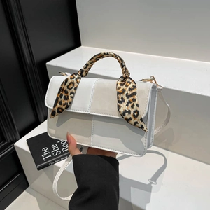 Chic white crossbody bag with leopard print scarf handle on minimalist background
