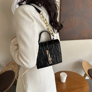 Elegant black embossed crossbody bag with golden chain strap and leather handle for women