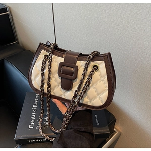 Close-up of quilted beige leather shoulder bag with dark brown trim and chain strap