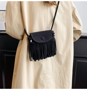 Detail view of black suede crossbody bag with long tassels and bohemian fringe elements