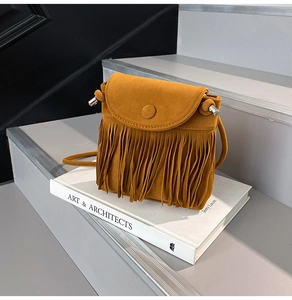 Close-up of mustard yellow fringe crossbody bag with suede texture on stone steps