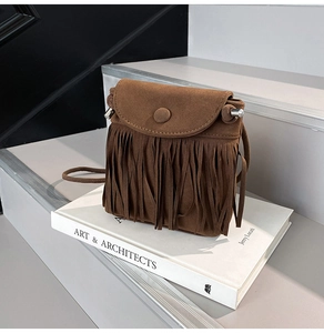 Detailed macro view of the brown suede fringe and clasp closure on bohemian crossbody bag