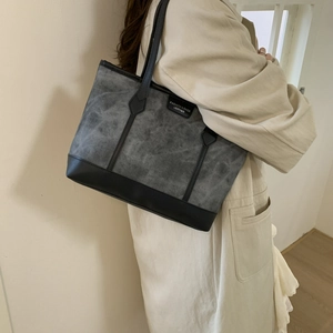 Minimalist grey canvas tote bag with black leather straps for elegant daily commuting