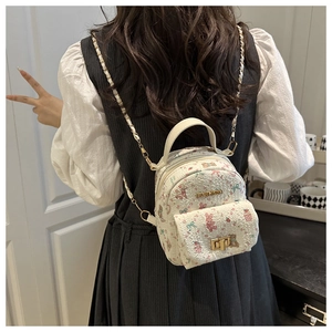 Detalle de mini mochila floral con correa de cadena dorada y letras de moda