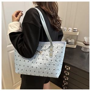 Détail du sac cabas matelassé bleu clair avec broderies papillon et pendentif nœud doré