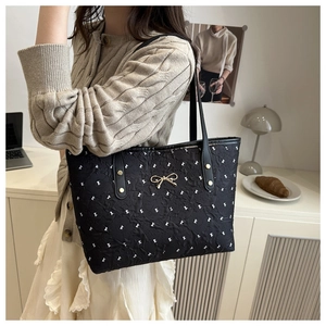 Détail du sac cabas plissé noir avec motifs de nœuds blancs et boucle dorée élégante