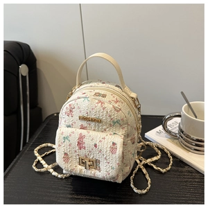 Detailed close-up of quilted floral cream backpack with gold hardware on table