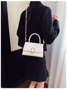 Close-up of white crocodile pattern shoulder bag with elegant golden oval buckle detail