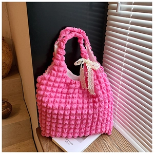 Detail of pink bubble texture tote bag with cream lace bow on the handle in bright setting