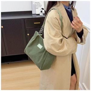 Detail of army green corduroy tote bag with chain strap and stylish white woven label