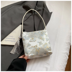 Dettaglio borsa in raso bianco con ricamo a farfalla blu e ciondolo a nappa lunga elegante