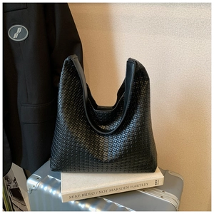Detail view of the black woven leather hobo bag texture on a stylish travel suitcase