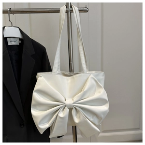 Dettaglio di una borsa tote bianca con un grande fiocco decorativo in ecopelle opaca