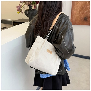 Detail of white corduroy tote bag with leather and silver chain shoulder strap