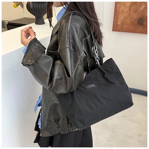 Detail of black corduroy tote bag showing vertical texture and silver metal chain strap