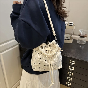 Sac seau blanc avec poignée en perles et broderie nœud porté par un mannequin