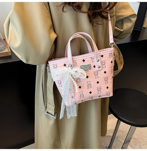 Détail du sac seau rose avec nœud en dentelle, breloque perle et motif d'ours