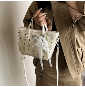 Détail du sac seau crème avec imprimé ours, nœud en dentelle et breloque en perles