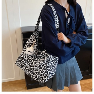 Détail du sac cabas léopard avec charme monstre en peluche blanc sur un modèle chic