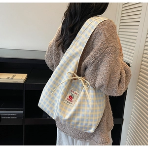 Detail of blue and yellow plaid canvas tote bag with handmade logo and adjustable strap