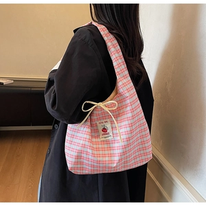Detail of pink plaid canvas tote bag with a handmade label and decorative bow accent