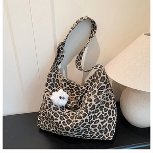 Détail du sac cabas léopard avec un porte-clés pompon blanc et une bandoulière large