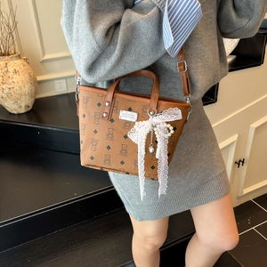 Sac seau vintage marron avec imprimé ours et breloques en perles porté par un mannequin