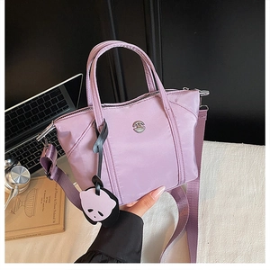 Detail view of light purple nylon dumpling bag with crossbody strap and panda charm