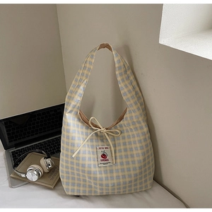Detail of yellow and blue plaid canvas bag with drawstring bow and embroidered patch
