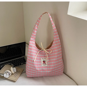 Detailed view of the pink and blue plaid canvas tote bag with a bow and handmade label