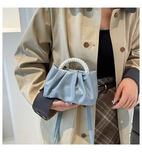 Detail of light blue pleated cloud bag with elegant white pearl handle and shoulder strap