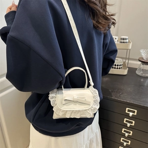 White crossbody bag with decorative bow and lace trim shown on a model