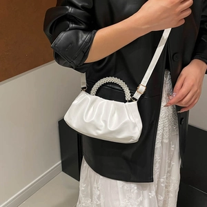 White pleated cloud bag with pearl handle and leather strap on model for stylish daily use